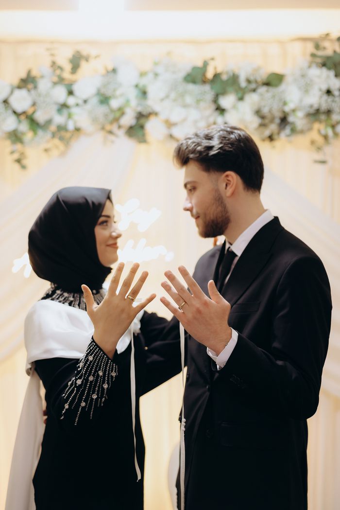 A Muslim couple celebrating their wedding with elegant attire and floral backdrop.
