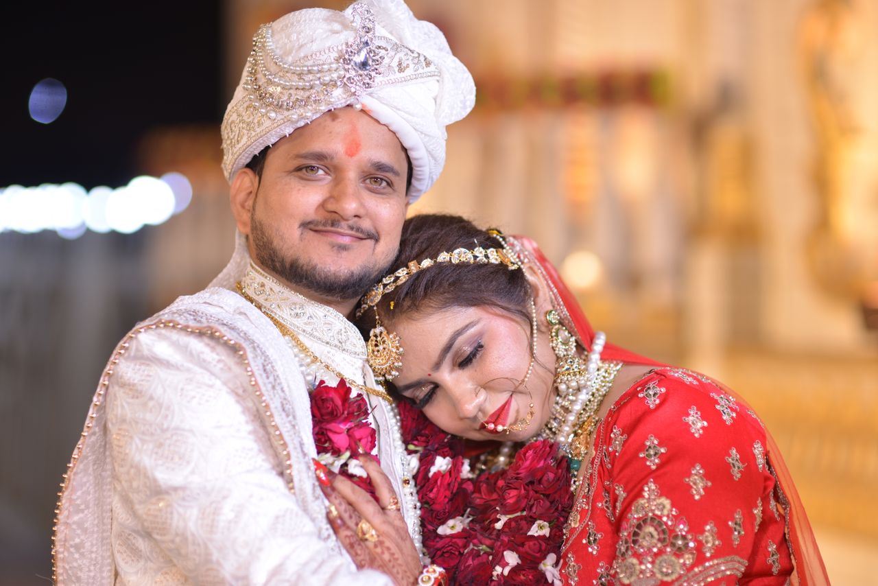 A joyful couple celebrates their Indian wedding in traditional attire, adorned with rich decorations.